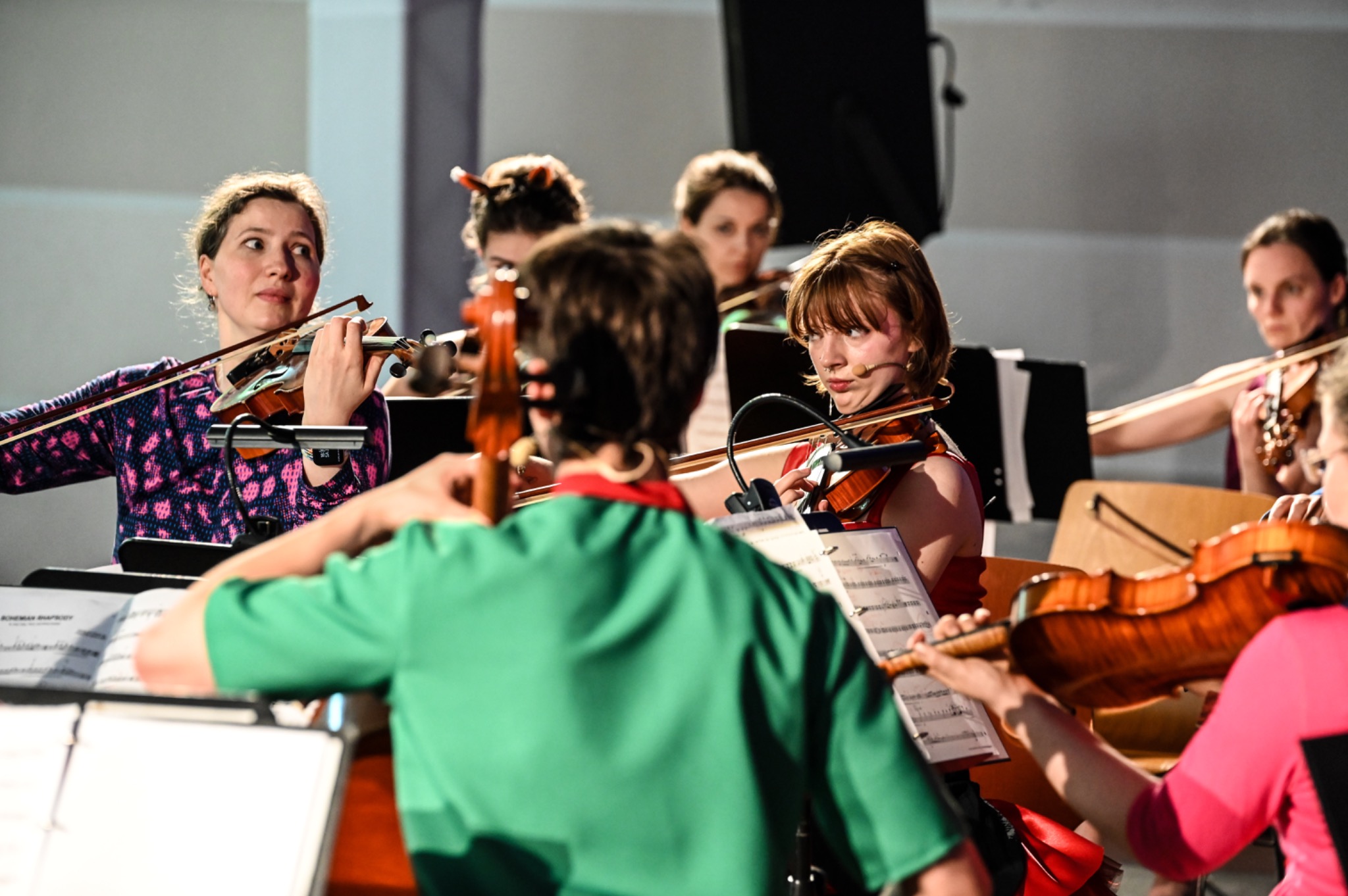 Junge und erwachsene Musikerinnen begegnen sich aufmerksam im gemeinsamen Orchesterspiel
